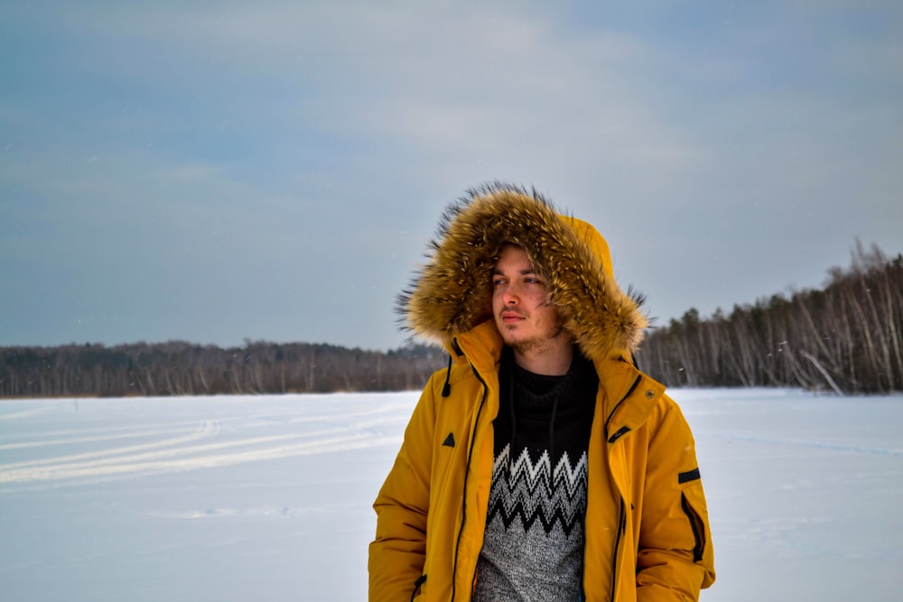 man wearing yellow pullover standing on snow field