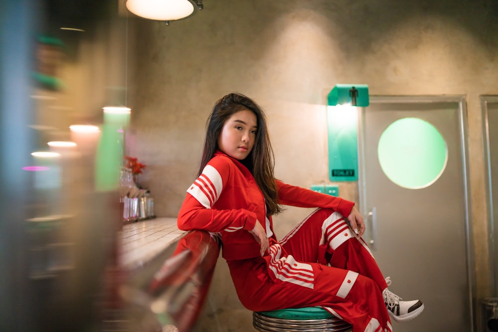 woman in red track set sitting on bar chair