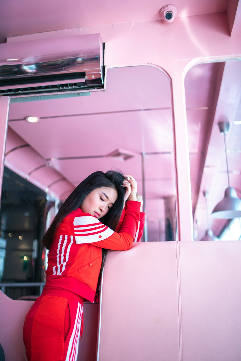 woman in red and white jacket and pants standing near pink painted wall