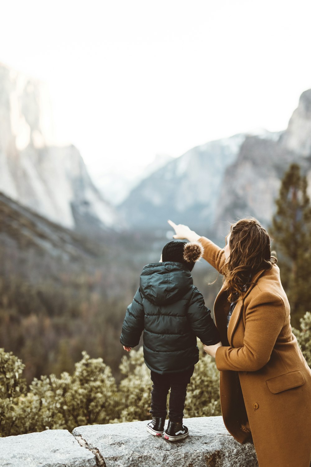 woman holding child by hand facing mountain