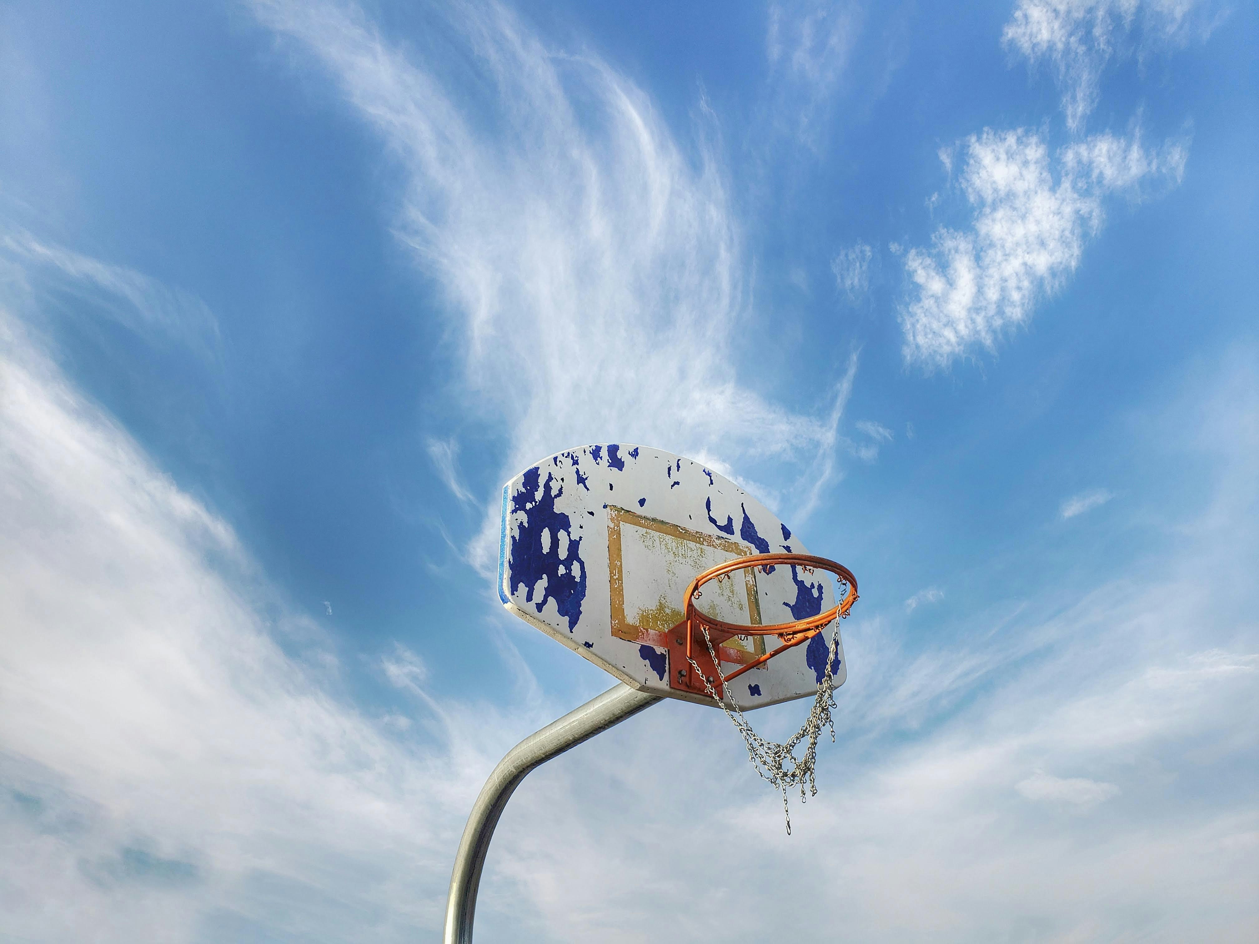 white and orange basketball hoop under white and blue sky