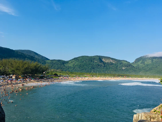 A vibrant photo of tourists enjoying a scenic beach in Lombok with a tour guide and rental vehicles nearby.
