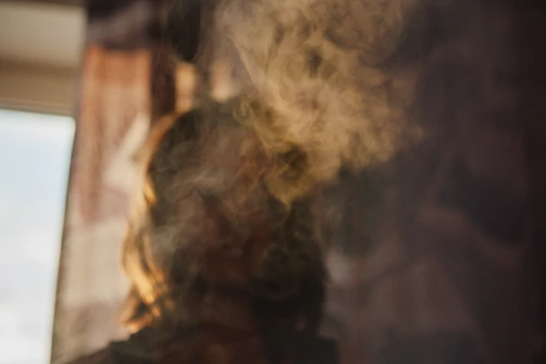 A woman hugging someone who is fading away into smoke, set in a heavy emotional atmosphere with a dark background and an expression of abandonment, in premium cinematic art style.