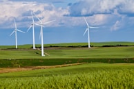 An aerial view of wind turbines spinning gracefully across a green landscape.