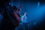 Close-up of two guitars being strummed in sync under warm stage lights.