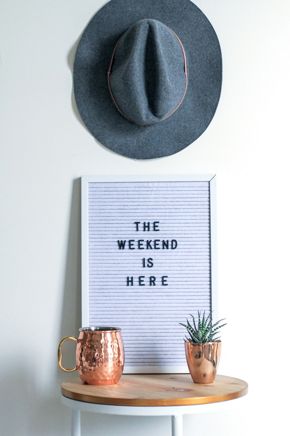 two brown vases on table and gray hat on wall