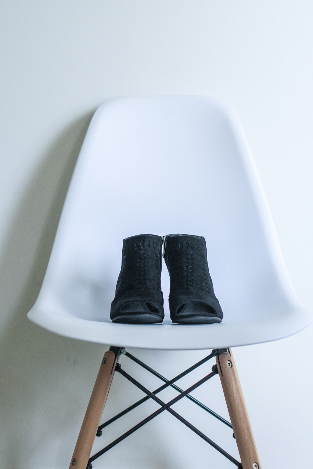 pair of black leather boots on white chair