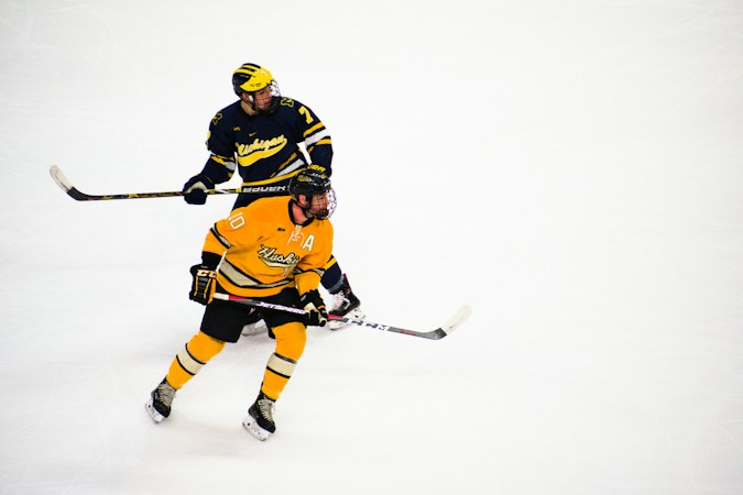 Two college-age hockey players battle for position on the ice during a game, similar to the action in UNLV's opening series
