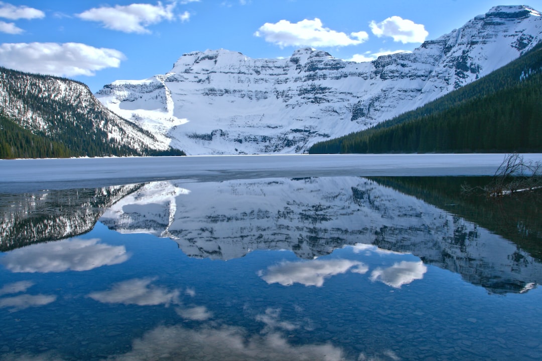 calm body of water surrounded with mountain during daytime