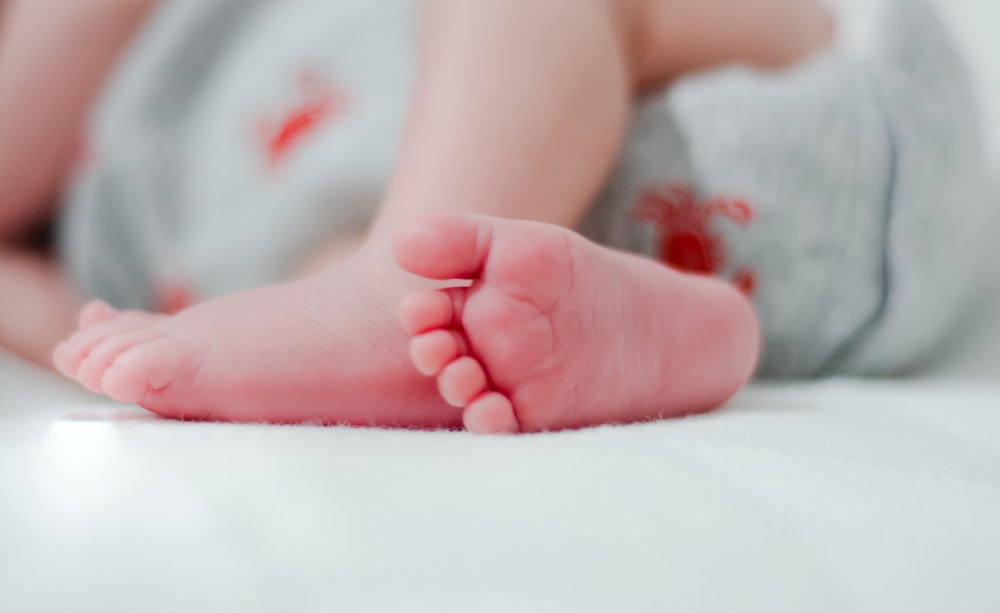 baby wearing white diaper showing foot