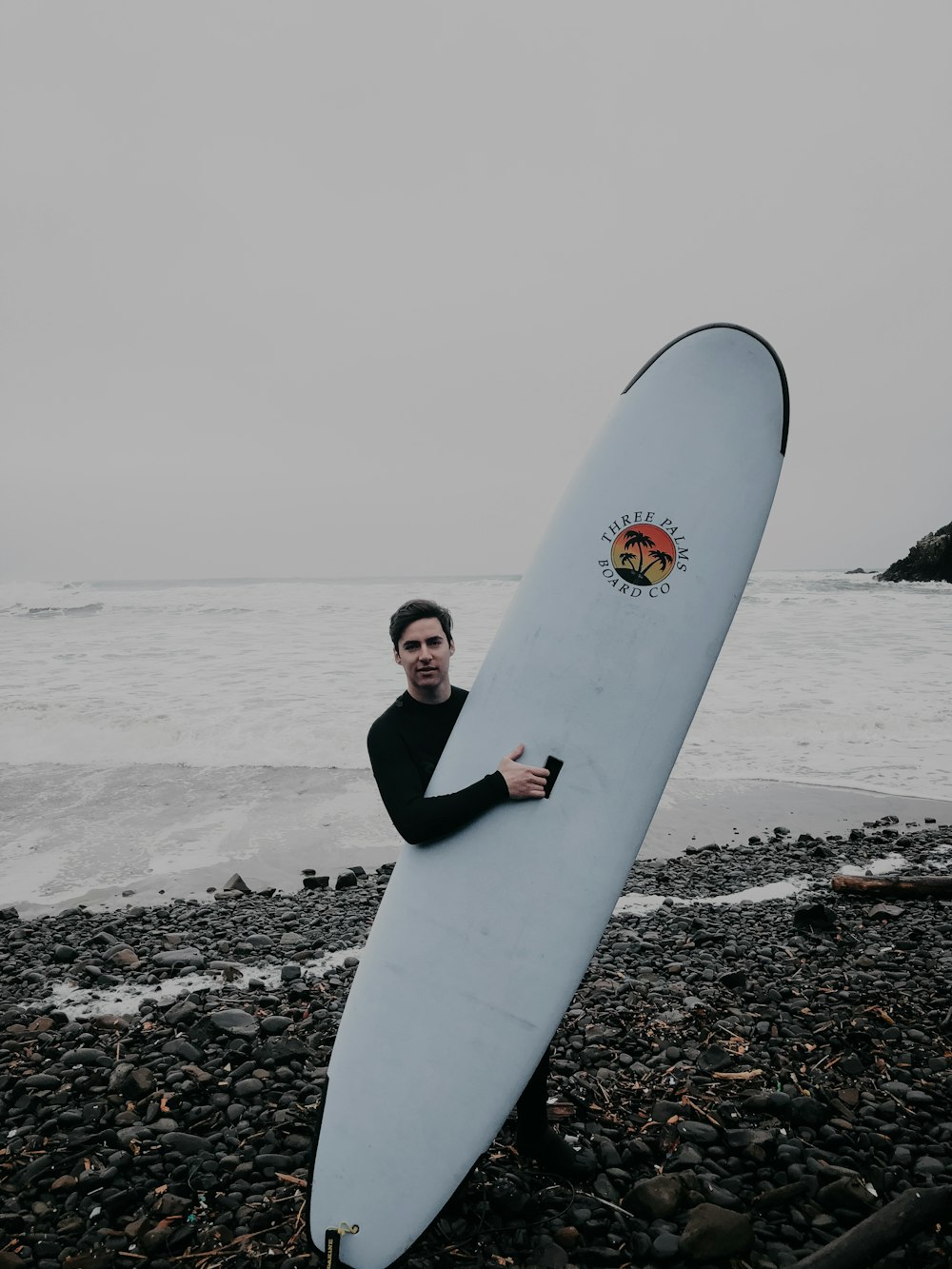 man holding white surfboard near seashore during daytime