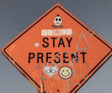 person pointing Stay Present road sign during daytime