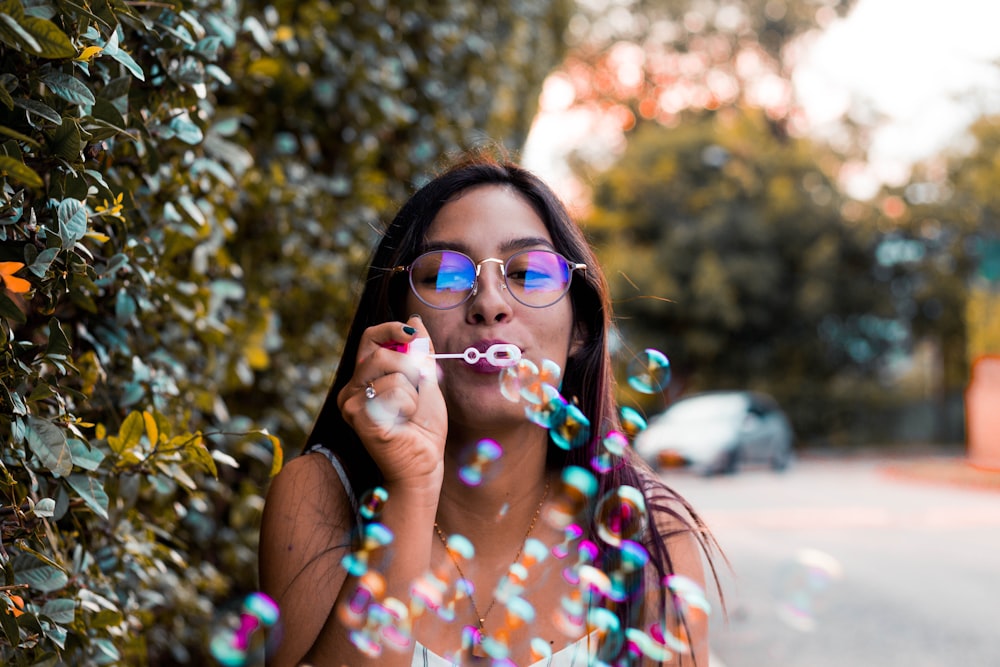 woman blowing bubble outdoor during daytime