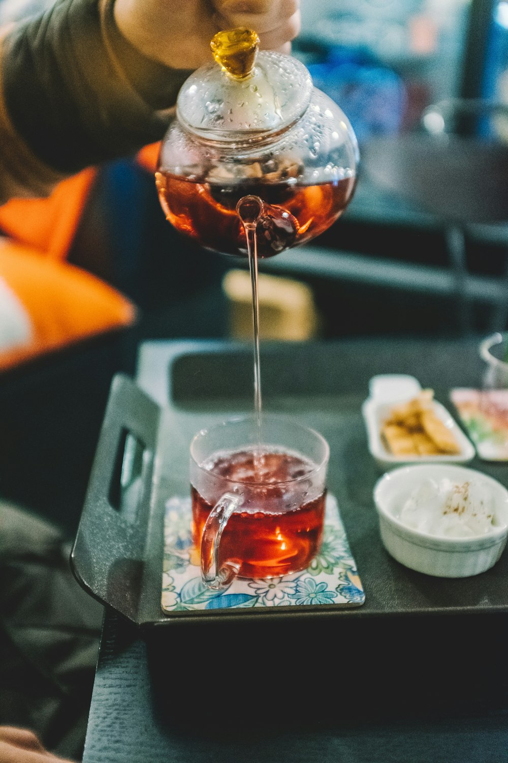 tea being poured out of clear glass kettle to cup