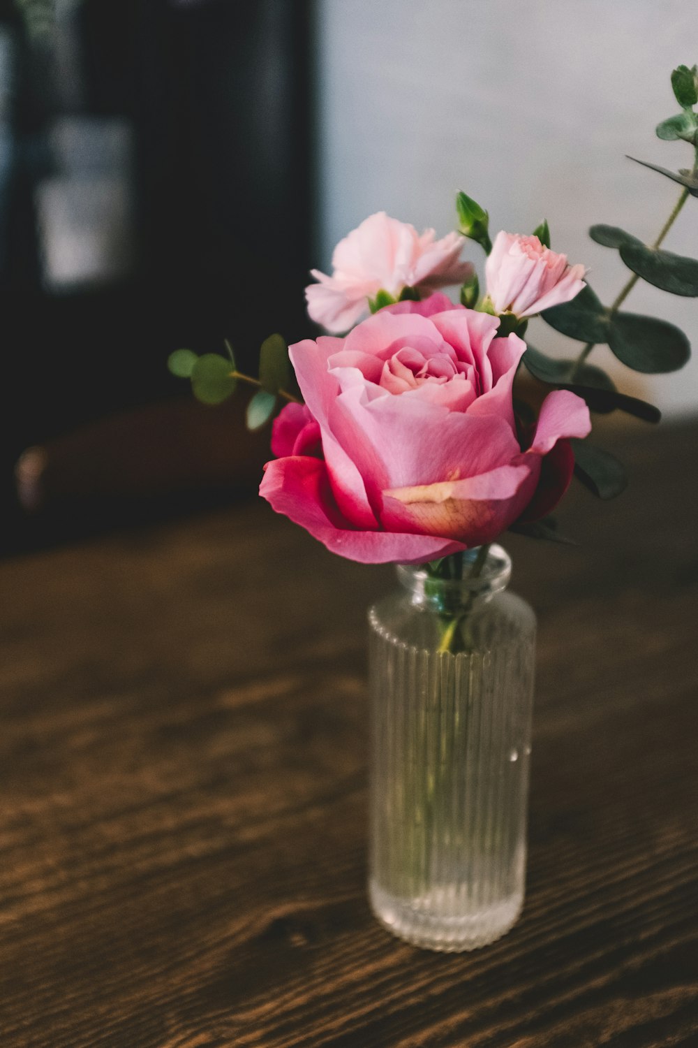 pink roses in clear glass vase on brown surface