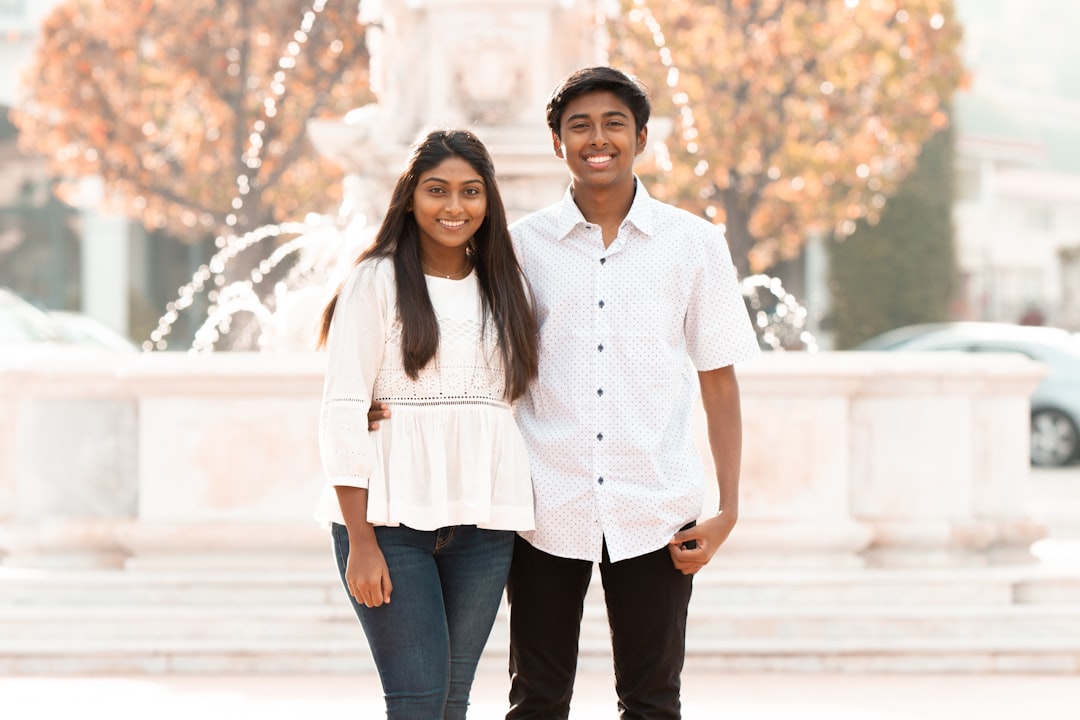 smiling woman and man standing near fountain during daytime