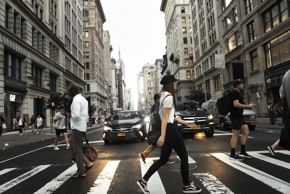 people crossing on pedestrian lane near different cars on road