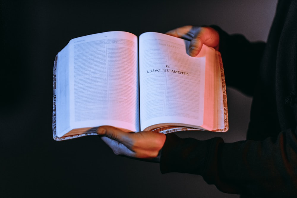 persona che tiene in mano un libro che mostra Nuevo Testamento