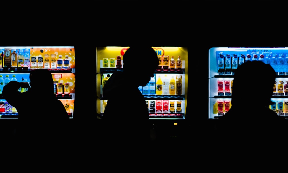 silhueta de pessoas em pé na frente de chillers comerciais