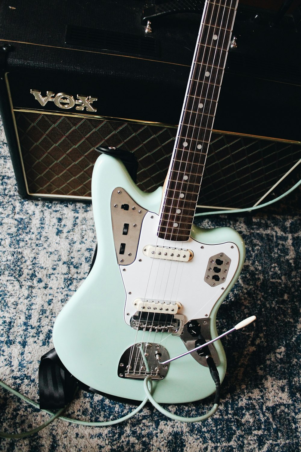 teal and white electric guitar near amplifier