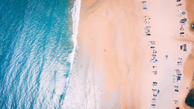 Wide shot of the turquoise ocean meeting the golden sandy beach with ATVs parked nearby.