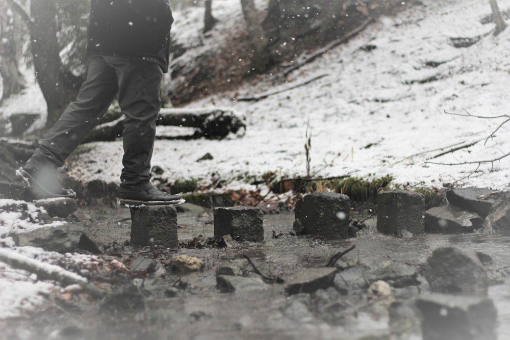 person wearing gray pants walking on snow covered field