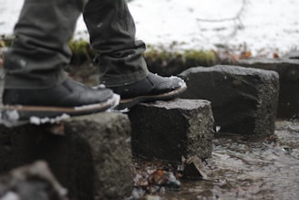 Close-up of worn hiking boots stepping carefully over ancient stones on a historic trail.