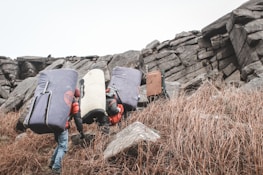 A scenic multi-day expedition group navigating rocky terrain with climbing gear.