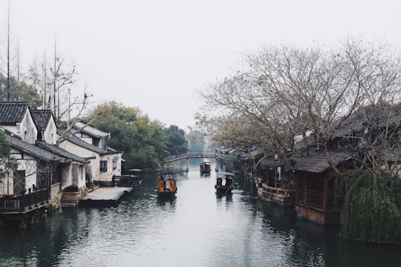 A serene boat gliding through the canals of Zhujiajiao ancient water town under soft afternoon light.