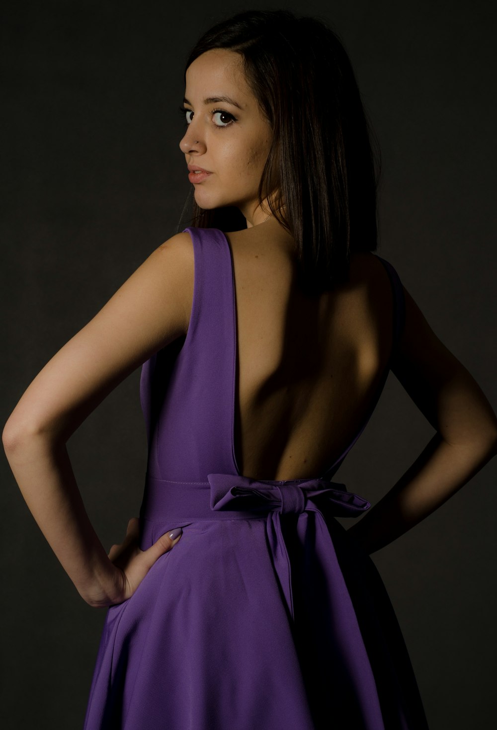 woman wearing purple backless dress looking back