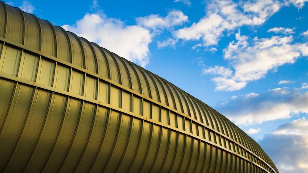 white clouds in blue sky over gold-colored metal structure