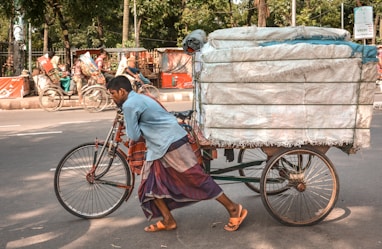 man pushing trike loaded with saks