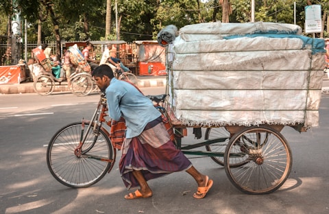 man pushing trike loaded with saks