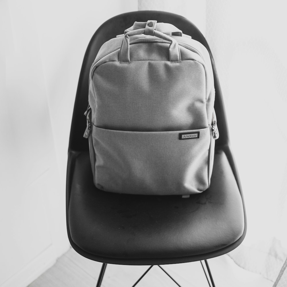 grayscale photography of backpack on chair