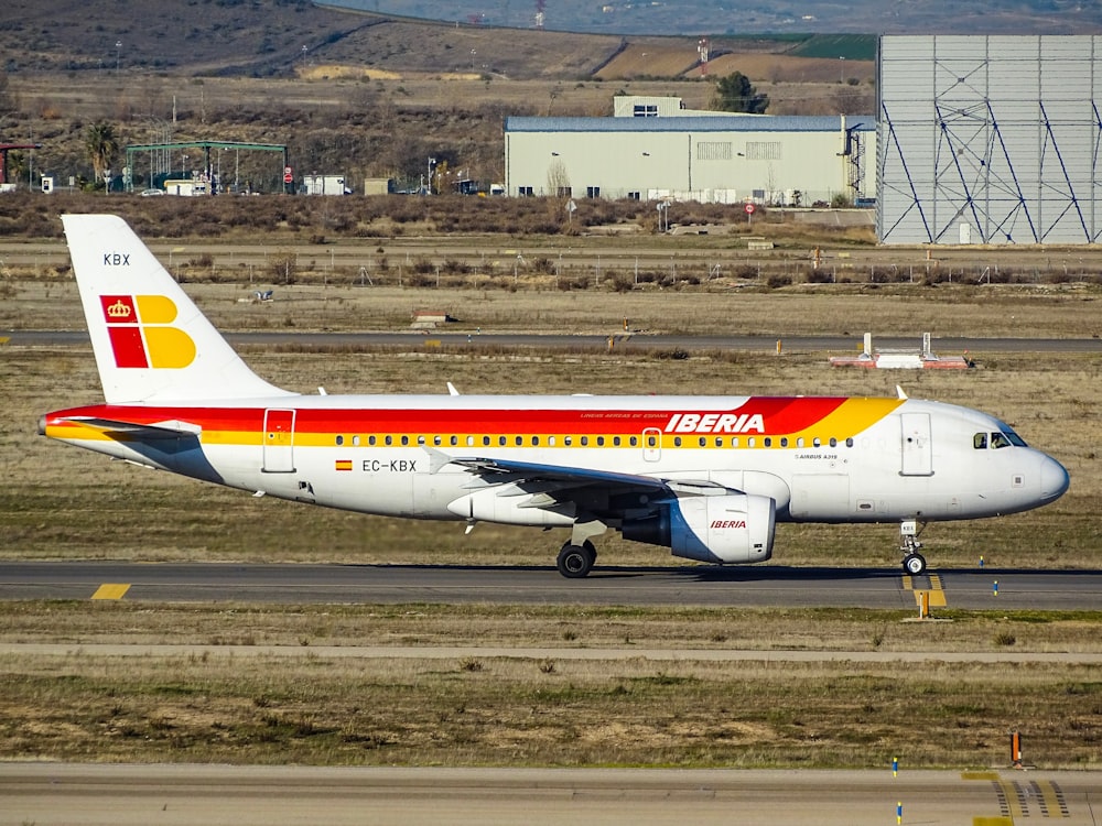 white and red Iberia airlines plane parked on runway