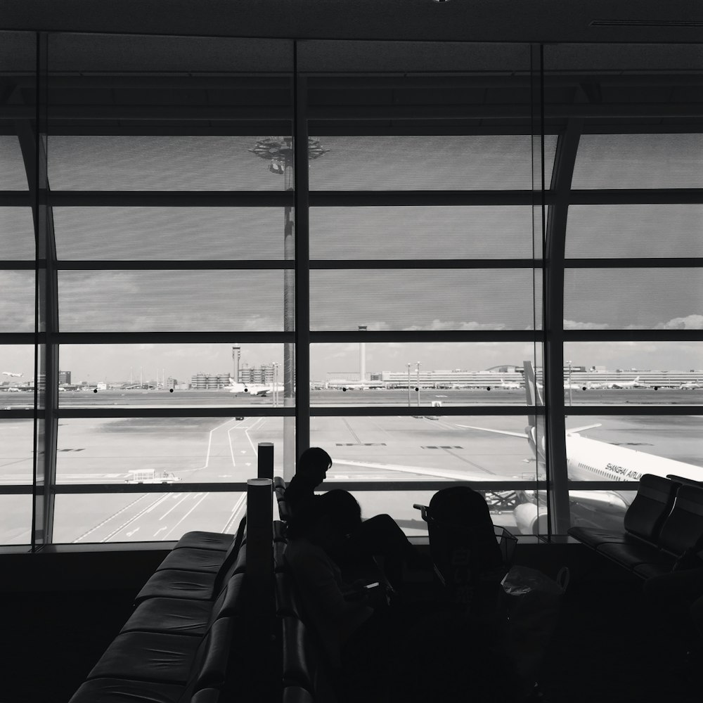 grayscale photography of people sitting inside airport