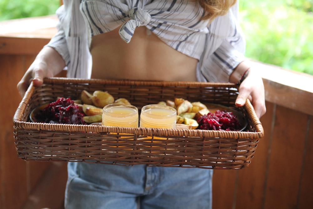 person standing and carrying basket with juice and pastry