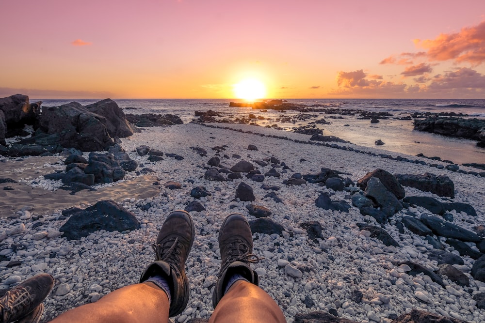 Persona sentada con pantalones marrones con vistas al mar durante la hora dorada