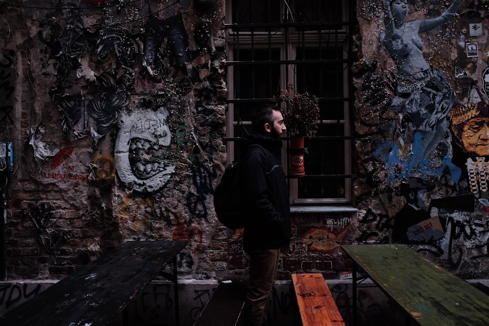 man standing beside concrete building