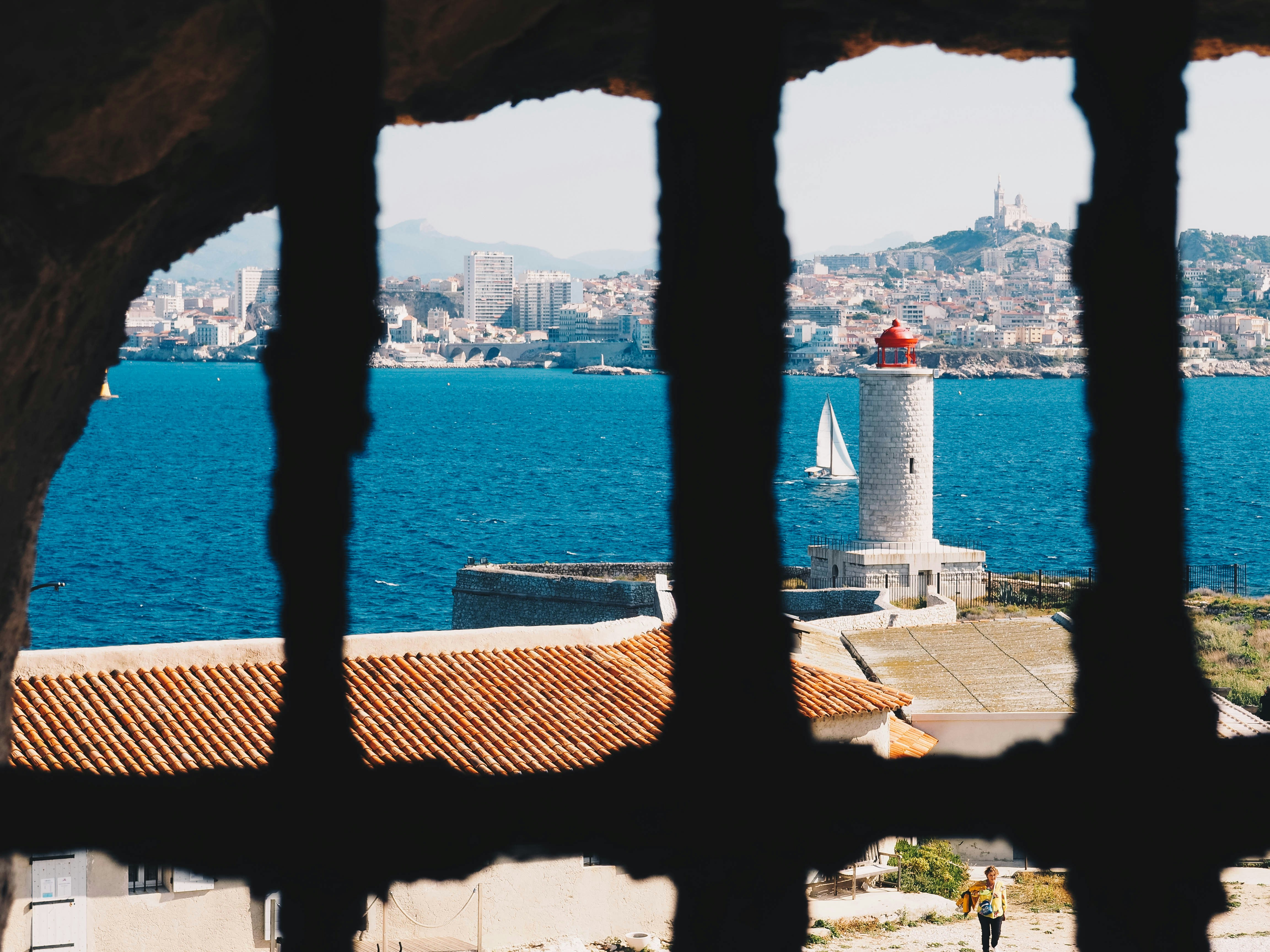 lighthouse near white sailboat on body of water