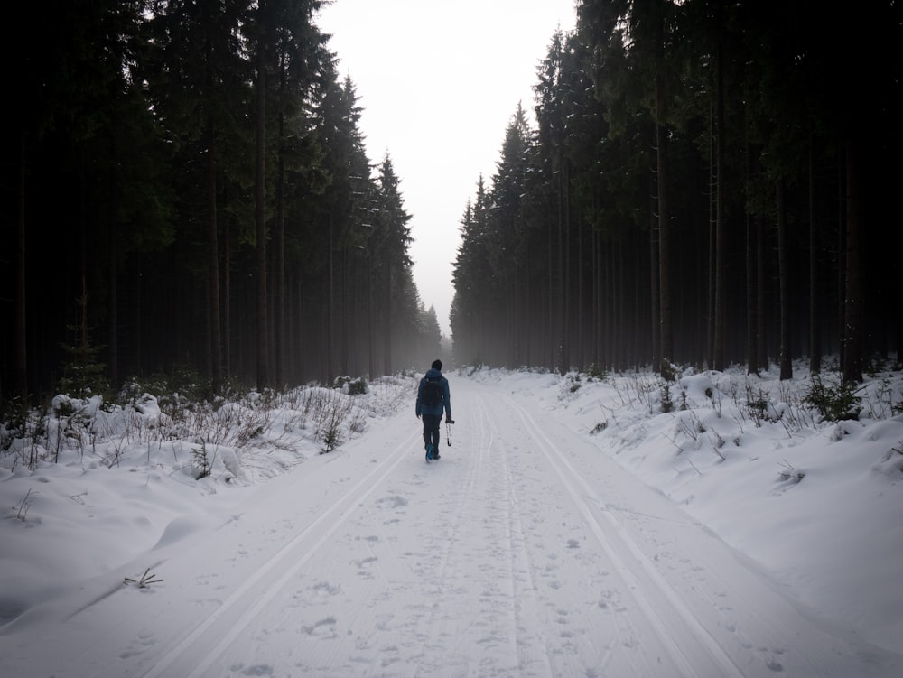 man walking on snow covered road