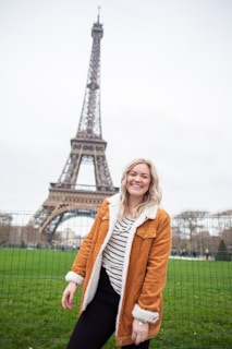 A smiling professional holding a work visa in front of an iconic European landmark.