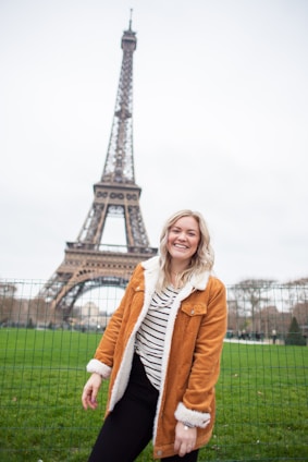 A smiling young professional happily holding a European work visa, standing against a backdrop of iconic European landmarks.