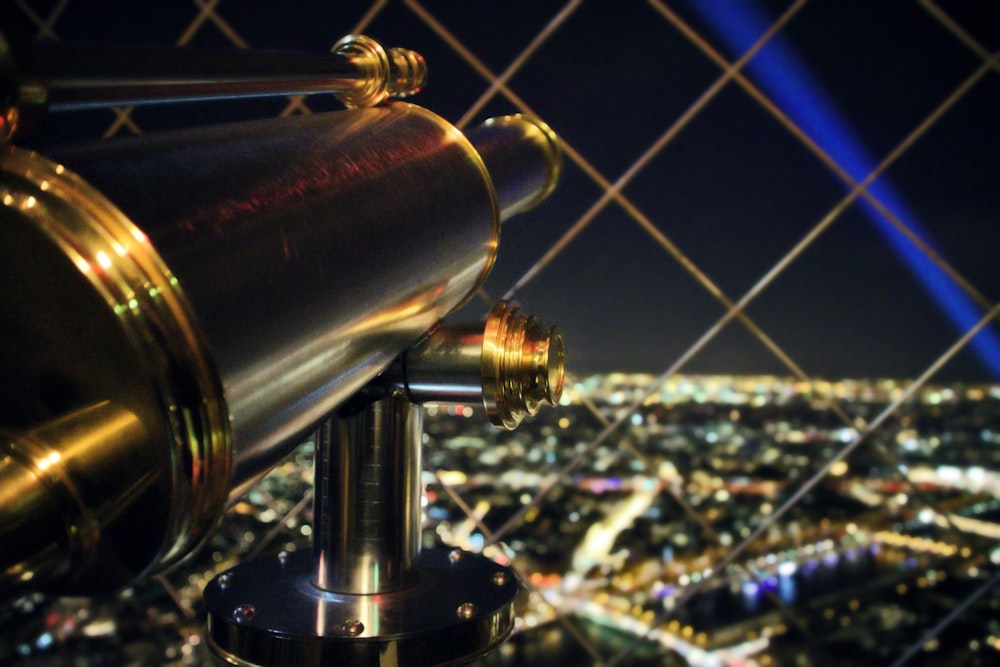 Messingfarbenes Teleskop mit Blick auf die Stadt bei Nacht