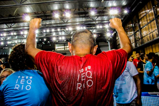 man in red shirt raising his hand inside building
