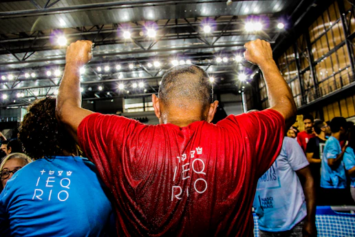 man in red shirt raising his hand inside building