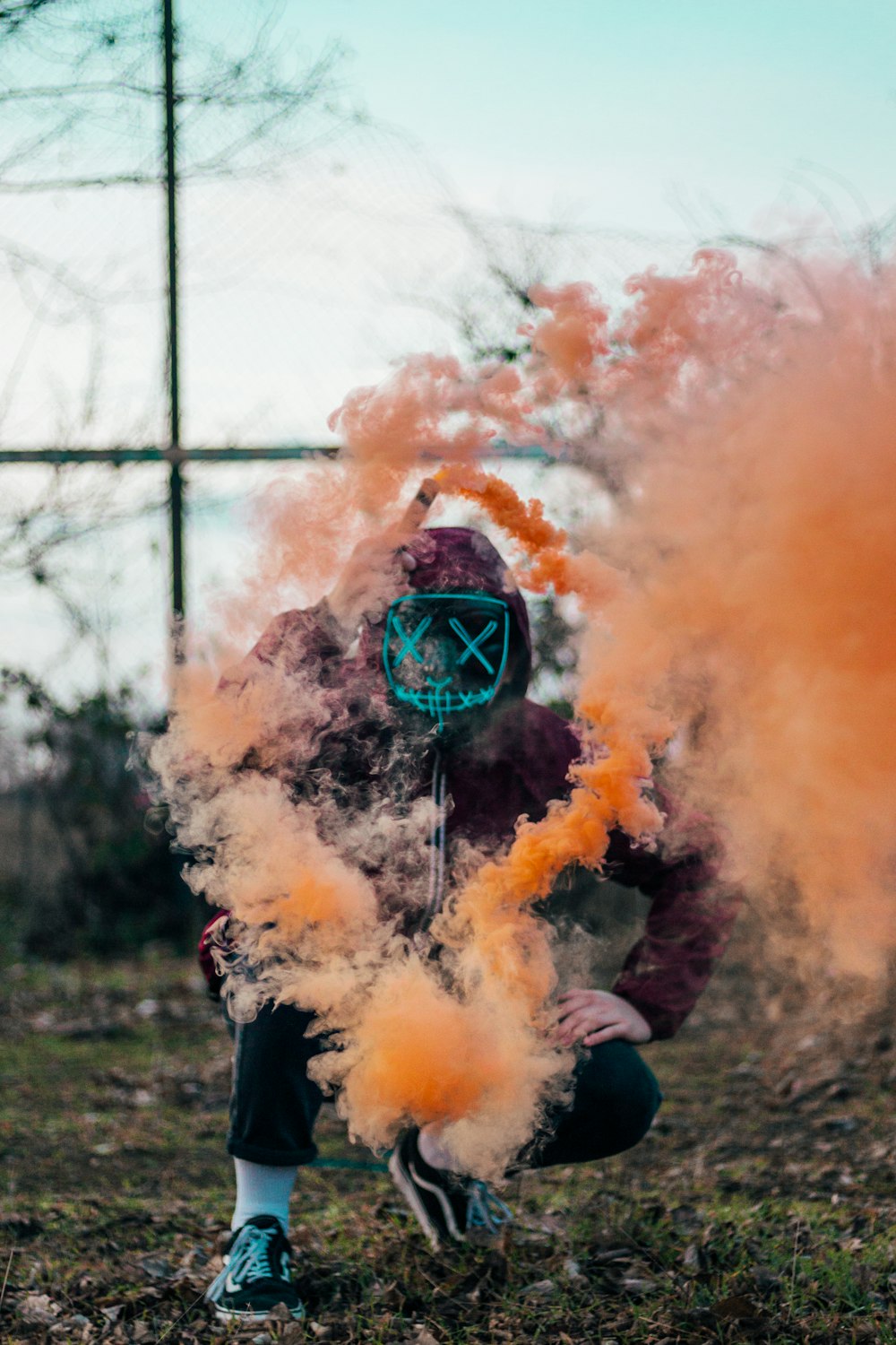 person in purple hoodie releasing orange smoke