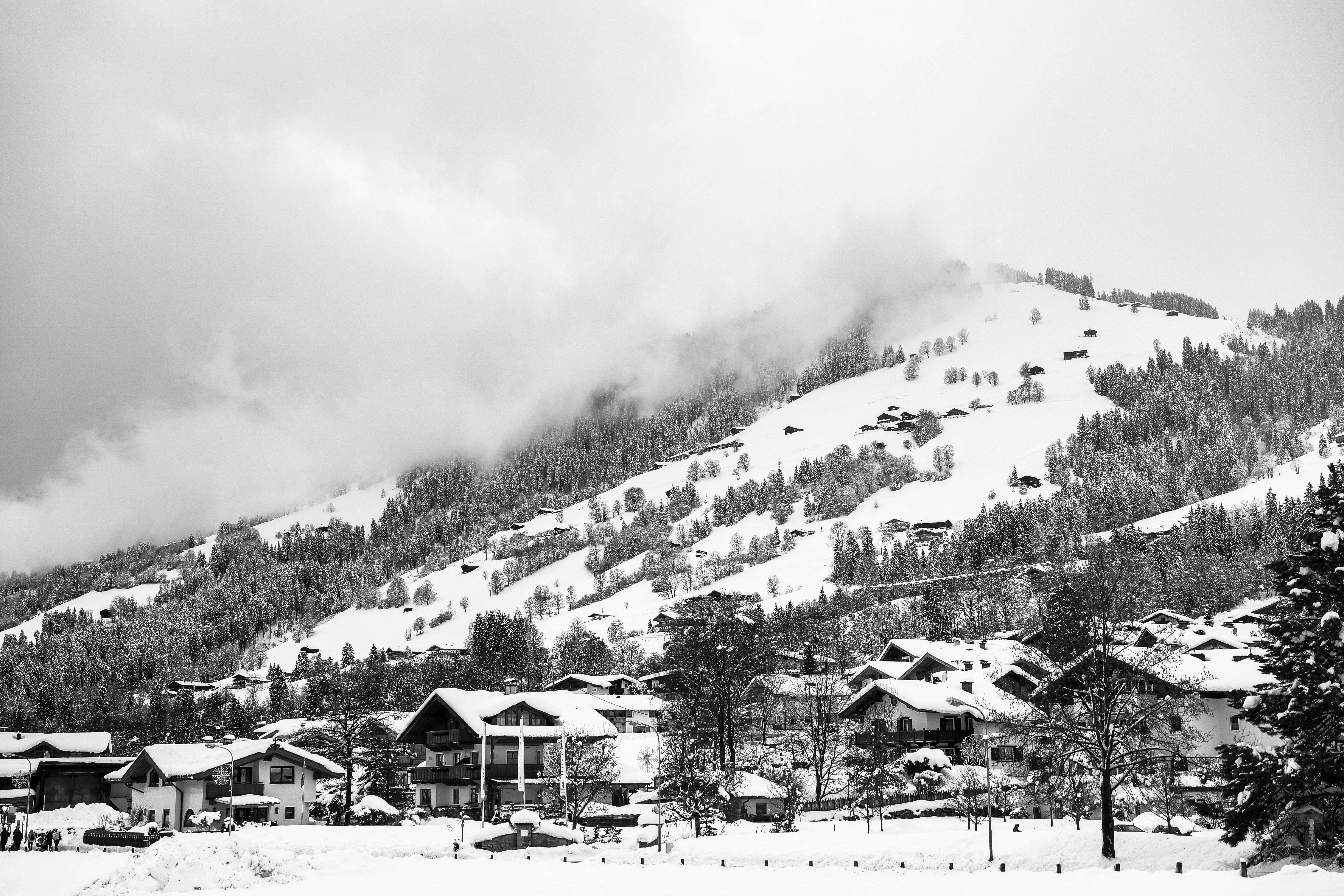 grayscale photography of village with mountain background