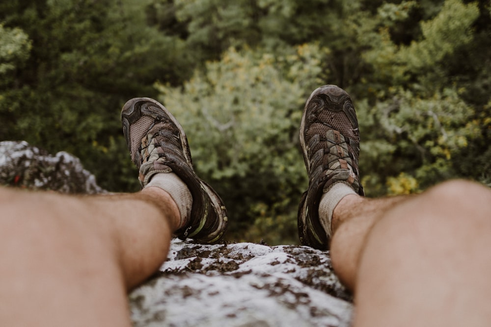 person wears trek shoes sits on cliff