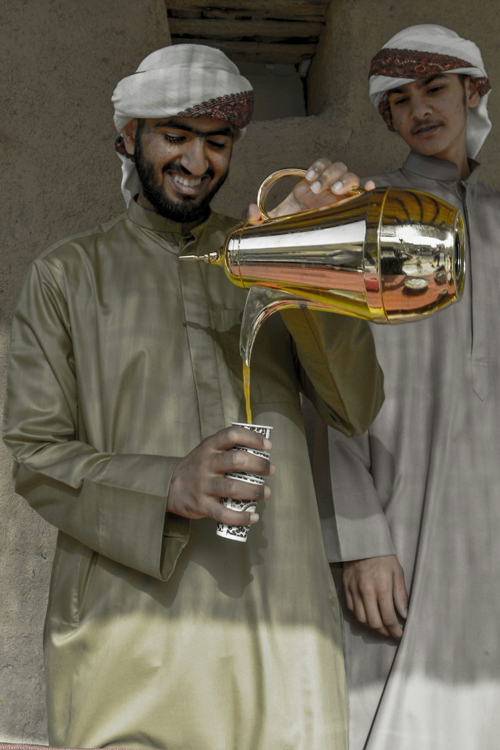 person holding gold-colored teapot